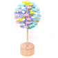 Rainbow multi-colored stacked-disc lollipop decompression toy on a round wooden base