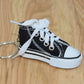 Black mini canvas sneaker keychain with white laces and attached metal key ring