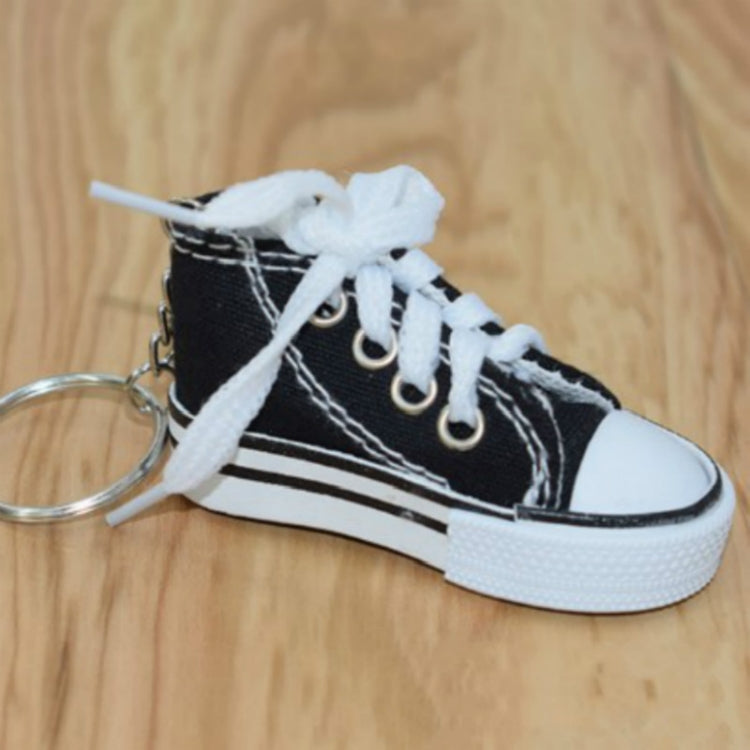 Black mini canvas sneaker keychain with white laces and attached metal key ring