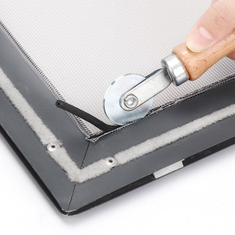 Window spline roller tool rolling along screen edge with metal wheel and wooden handle