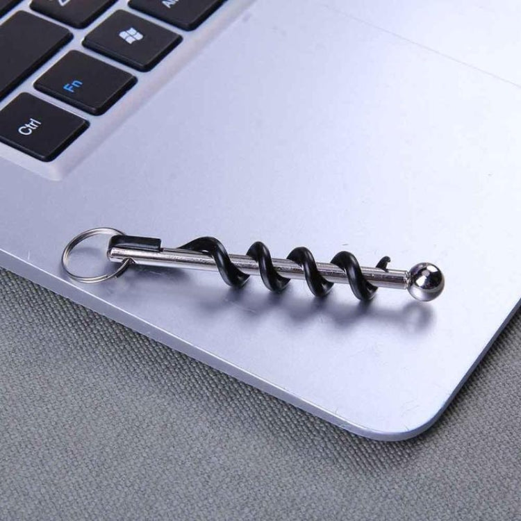 Corkscrew key ring attached to laptop edge, black spiral with round key loop