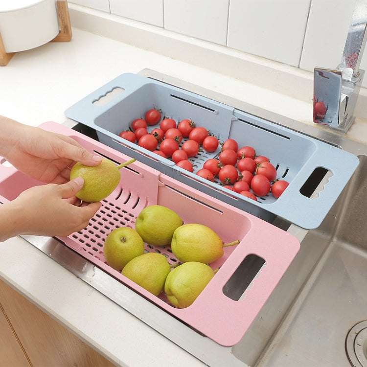 Pink plastic dish drain basket holding washed vegetables and fruits on sink