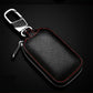 Dark leather key pouch with metal clip and ring, red piping, zipper, embossed texture