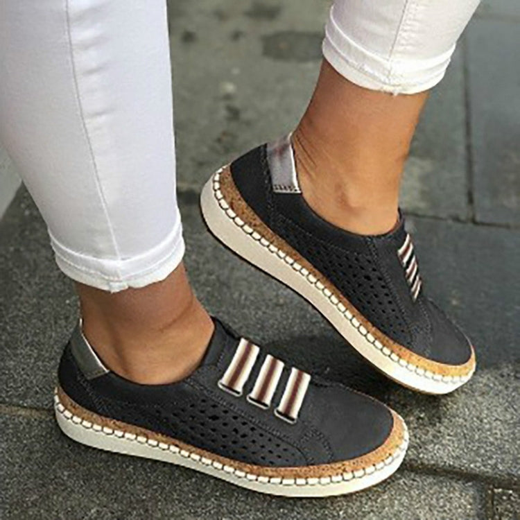 Black perforated slip-on sneakers with striped metal accent and cushioned collar