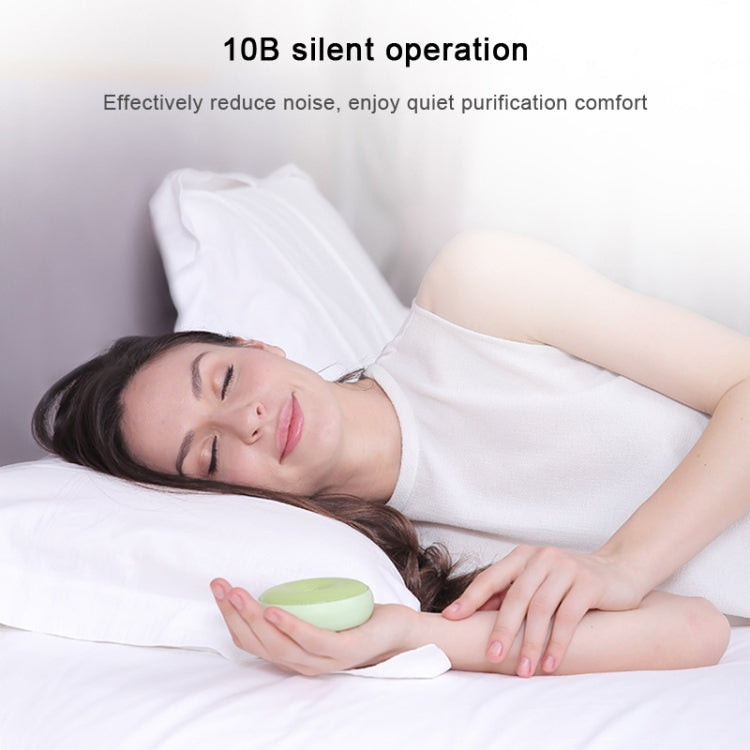 Portable round air purifier with mint-green casing and vented top grille.