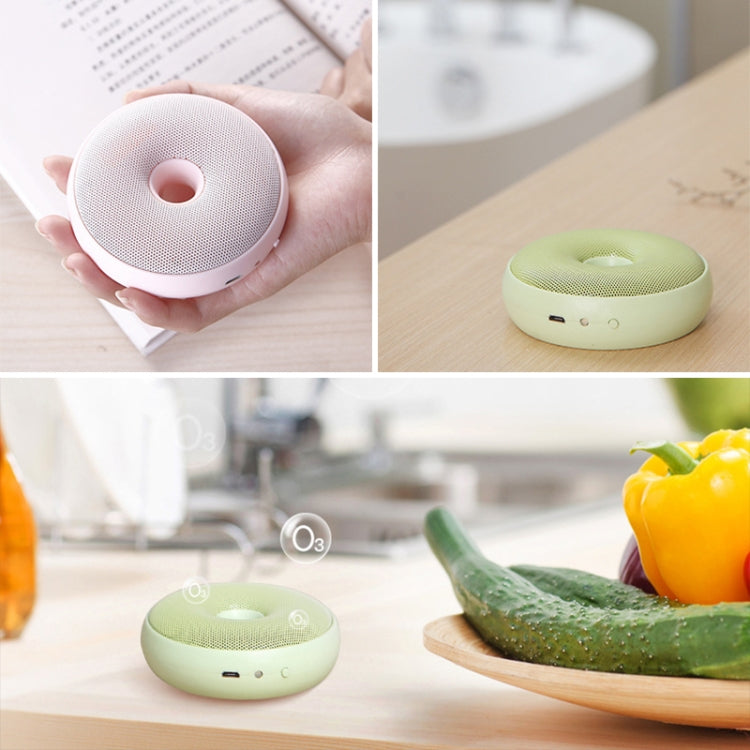 Mint-green portable air purifier on tabletop, showing top grille and indicator lights.