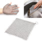 Square stainless steel mesh scrubber pad held in hand, with ring on corner