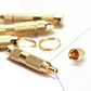 Close-up of gold-toned ear spoon tool with ring and tapered applicator tip