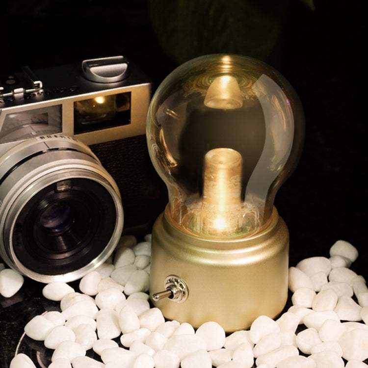 Gold USB night light with glowing bulb and metal side knob over white decorative balls