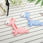 Pink and blue fawn-shaped silicone teethers with doe-face heads on a lined sheet