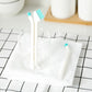 White and teal double-head cleaning brushes standing in a cup on a countertop