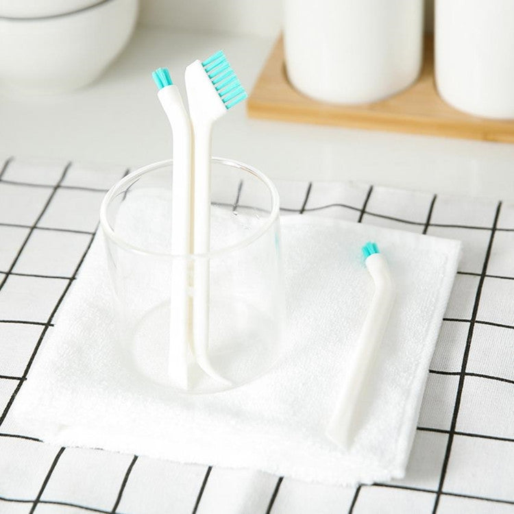 White and teal double-head cleaning brushes standing in a cup on a countertop