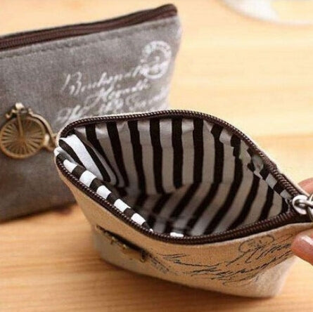 Gray coin purse open to striped lining; zipper top with brown edge trim