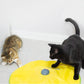 Yellow cat playing mat with gray motor dome, with cats watching from either side