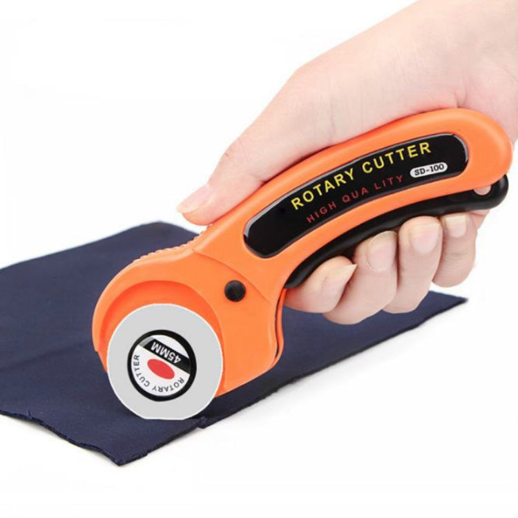 Orange rotary cutting tool with round blade, held over dark fabric cloth