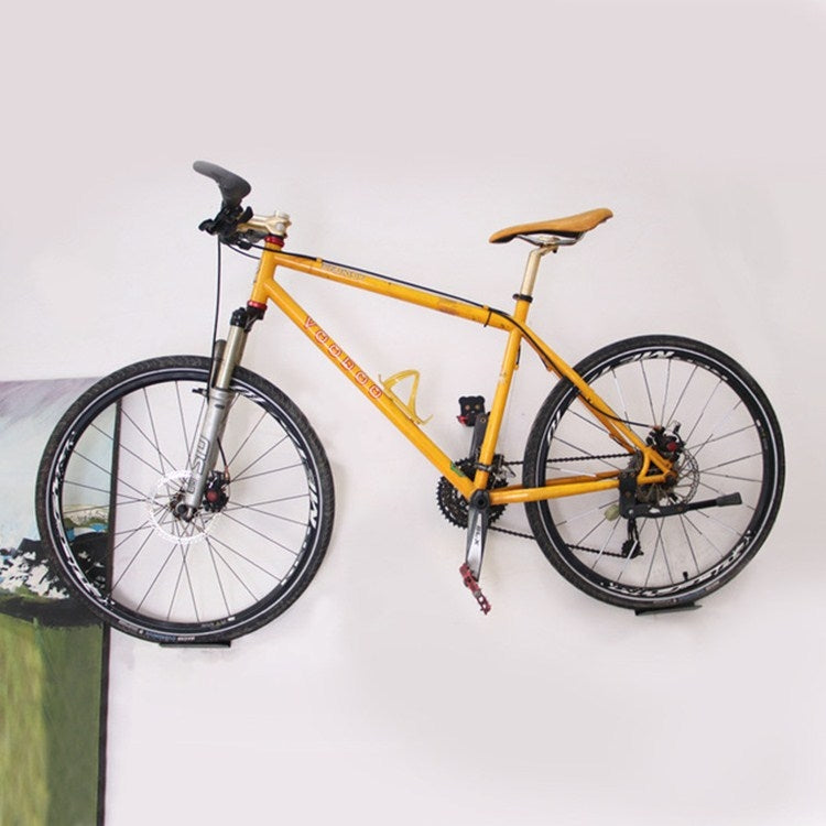 Bicycle parked on wall hook rack, front wheel supported by black holder
