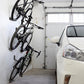 Multiple bikes stored on wall-mounted hook rack with black cradle supports