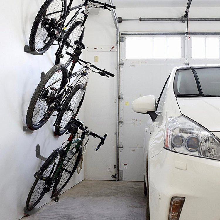 Multiple bikes stored on wall-mounted hook rack with black cradle supports