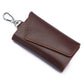 Brown leather keychain pouch with stitched snap flap and metal keyring, litchi texture.