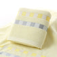 Cotton bath towel roll with off-white terry texture and yellow check stripe border