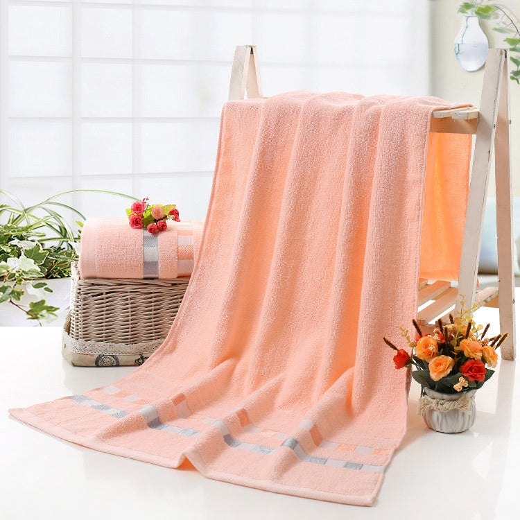 Cotton bath towel in light coral with checkered gray border and plush terry loop pile