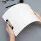 White clipboard folder with metal clip, held by hands above a blank sheet.