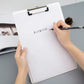White clipboard with metal clip and hand writing on the paper.