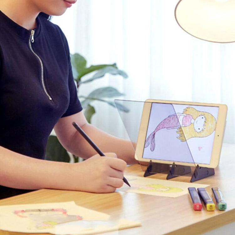 Optical tracing board with tablet showing a sketch and artist drawing on paper