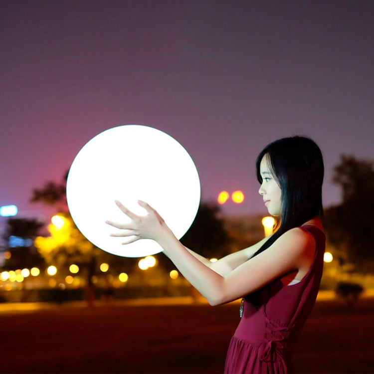 Round LED globe light held in front of a person, glowing bright white