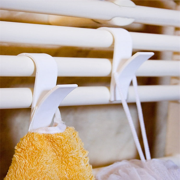White plastic towel rack hooks holding a yellow towel and a small cloth on a rail