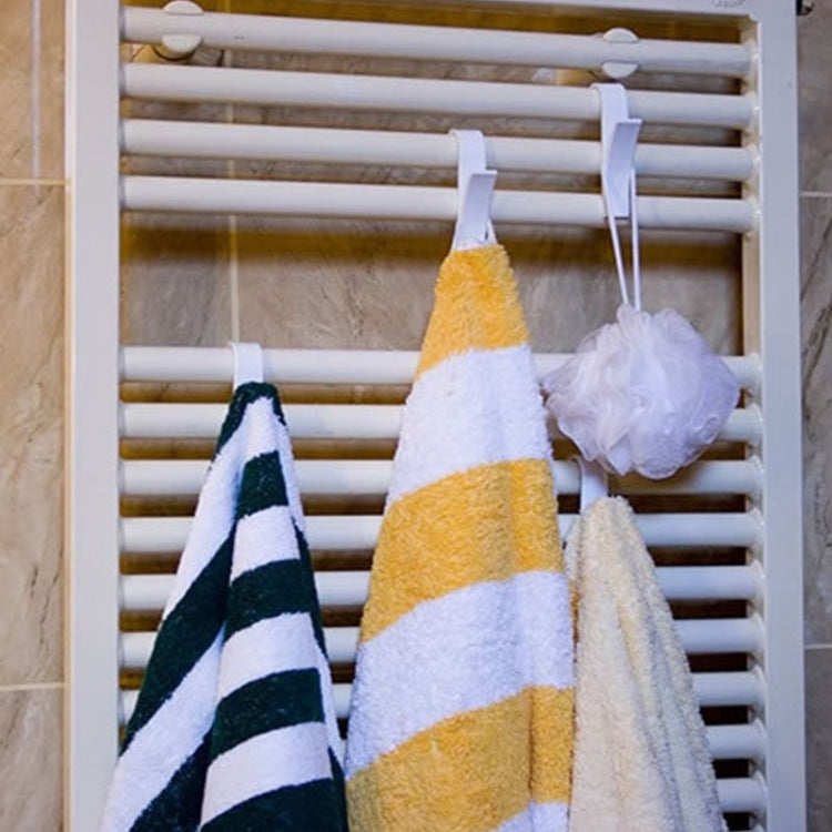 White plastic towel hook rack on slatted rail, holding yellow and striped towels