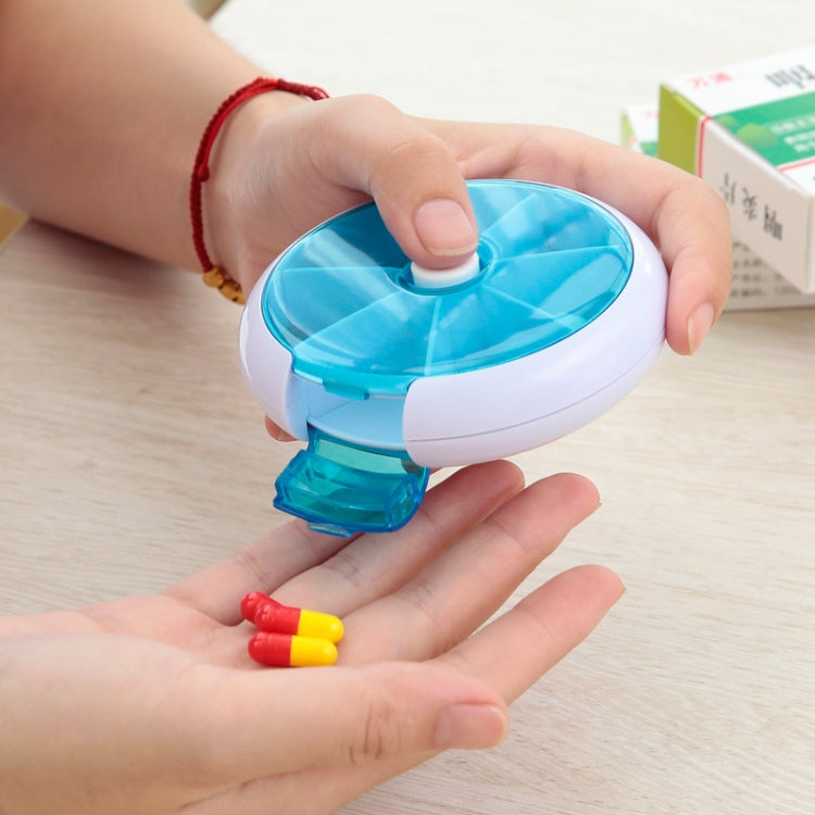 Blue rotating plastic pill box open, hand holding it with small pills visible