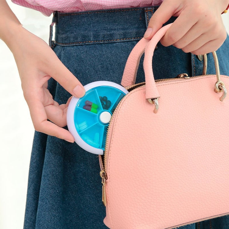 Blue portable rotating pill box stored in a denim pocket