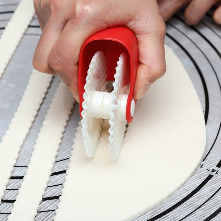 Hand using red pasta cutting wheel with white ridged roller on dough