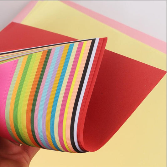 Multicolor striped craft paper sheets with a red sheet underneath, held in hand.