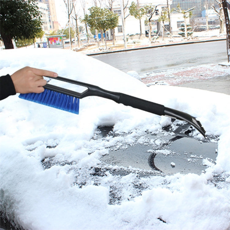 Blue car windshield snow brush clearing snow from glass surface