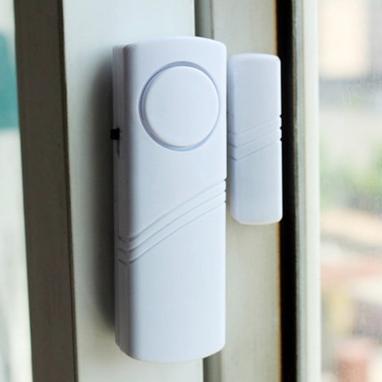 Wireless door/window alarm sensor mounted on door frame, white with circular button