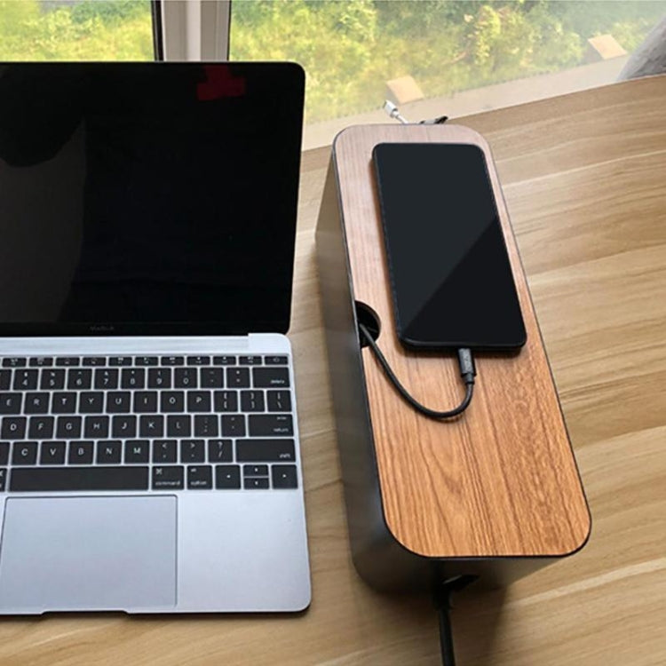 Black cable organizer with wood-look top holding a smartphone and charging cable