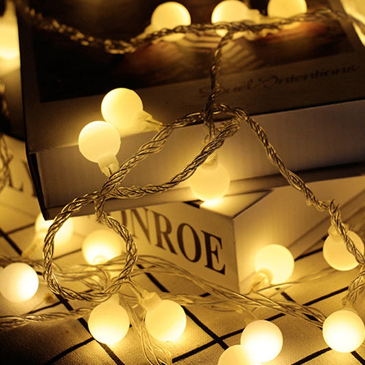 LED ball light string with warm white glowing bulbs across a wire strand