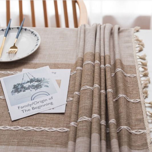 Beige cotton-linen tablecloth with tassels and rolled fabric texture detail