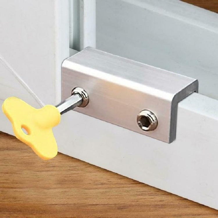 Anti-theft door stopper with metal bar, screw hole, and yellow key on wood surface