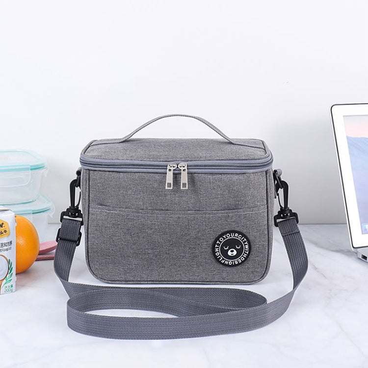 Gray lunch cooler bag with top carry handle, front logo patch, and zippered main compartment