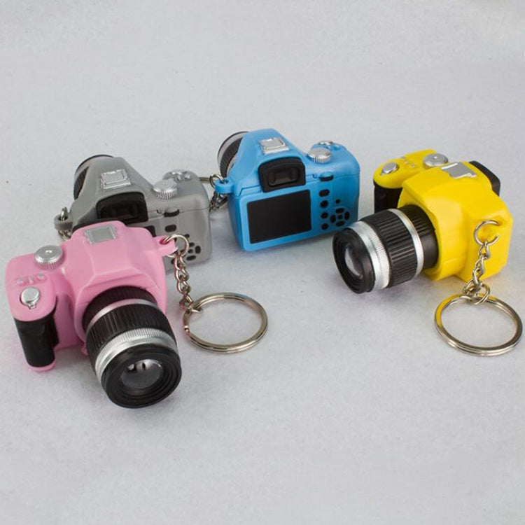 Four mini SLR camera keychain pendants in pink, gray, blue, and yellow