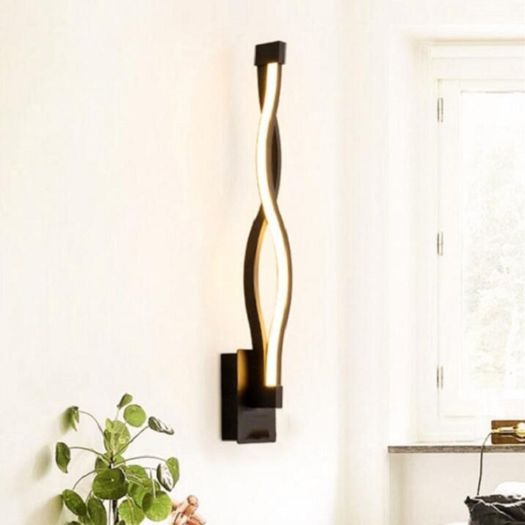 Black LED wall sconce with vertical curved metal body, emitting warm light