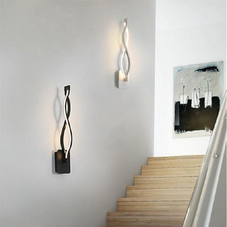 Black LED wall sconce with curved metal design, warm light glowing on wall
