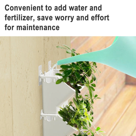 White vertical wall planter box with attached green plants and hanging cups