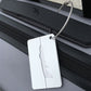 Silver brush aluminum luggage tag on suitcase zipper, airplane cutout and rope loop