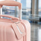 Rose pink brush aluminum luggage tag with airplane cutout and braided rope loop on suitcase