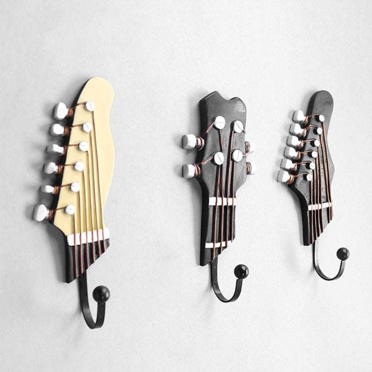 Set of three guitar-shaped wall hooks: black, cream, and dark gray, each with curved iron hook