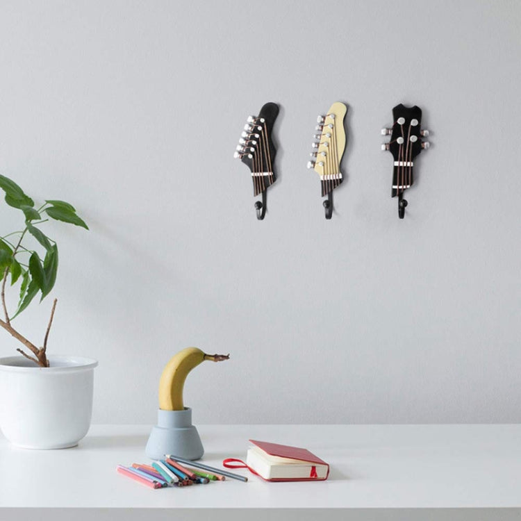Three small guitar-shaped wall hooks in black and cream, each with curved iron hook